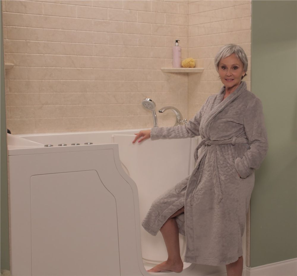 Walk in tub with a low step door, shown with a homeowner beside it