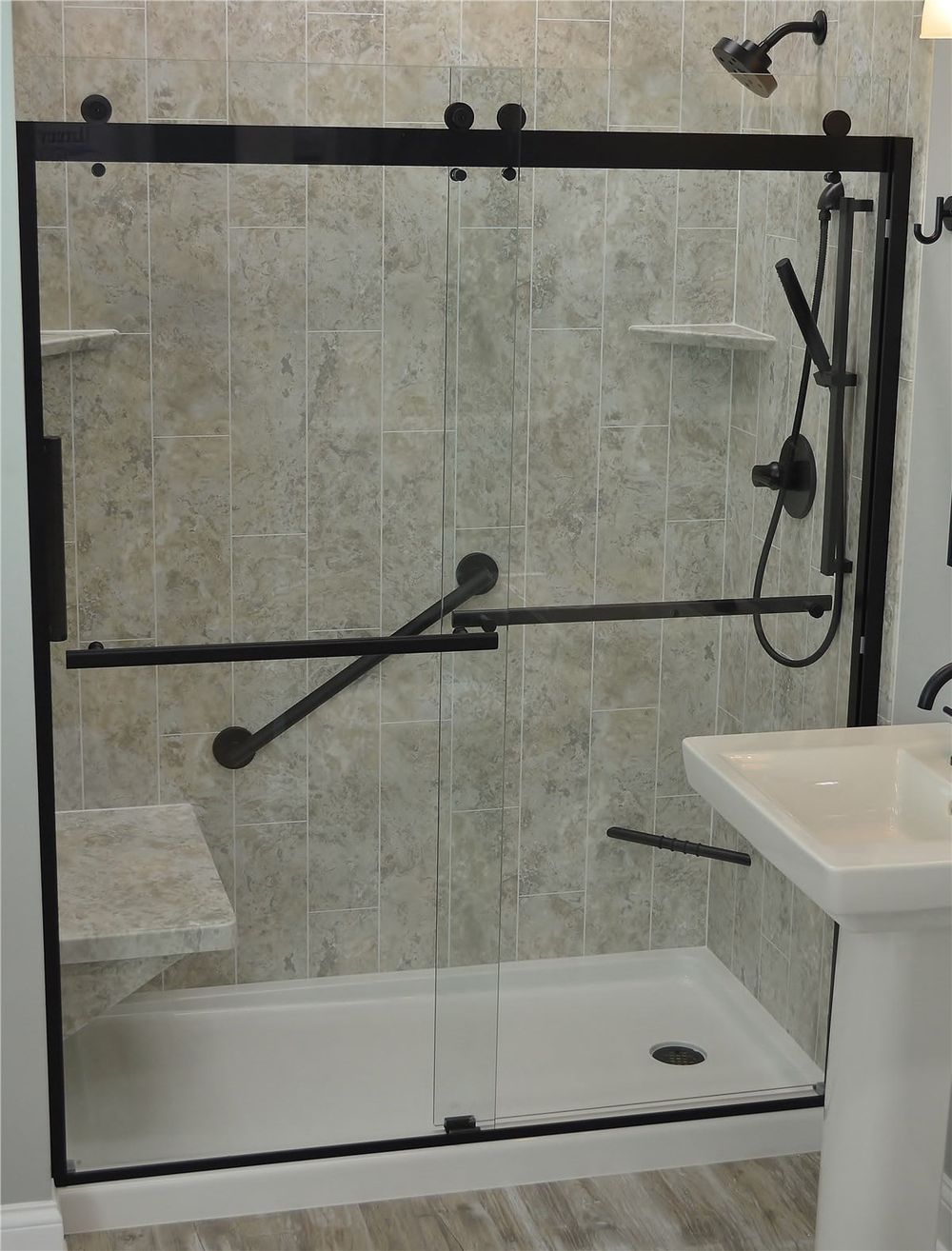 Walk in shower with a marble look wall and a brushed gold shelf