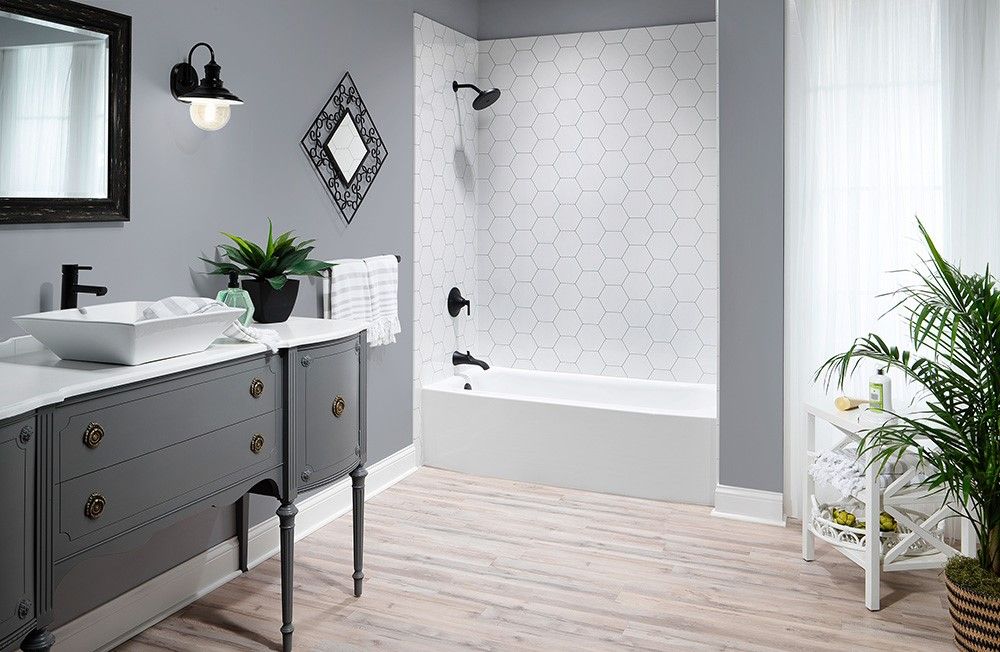 Tub with a white hexagon tile look surround and a grey double vanity